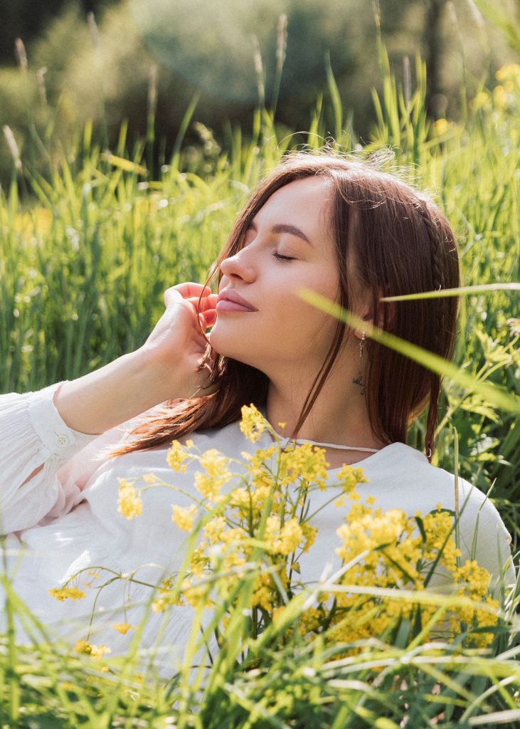 Young woman enjoying relaxation in a vibrant summer meadow with yellow flowers.
